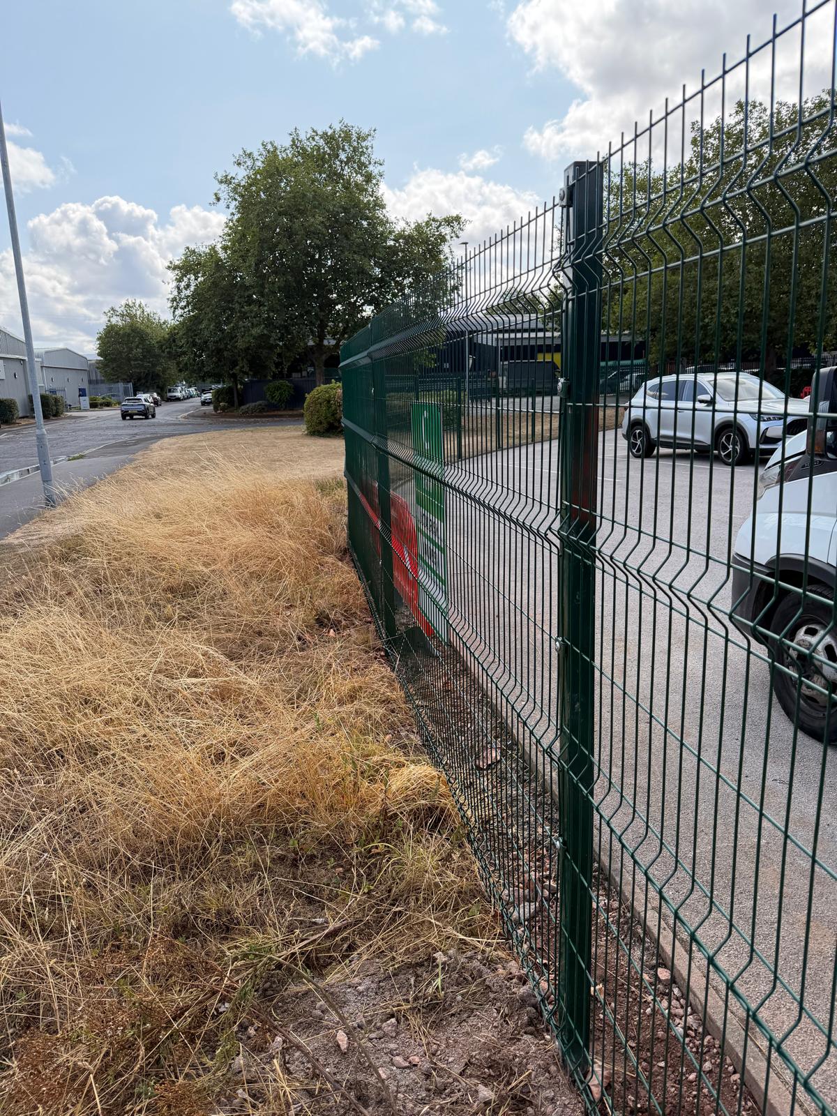 Green mesh security fencing around a commercial car park