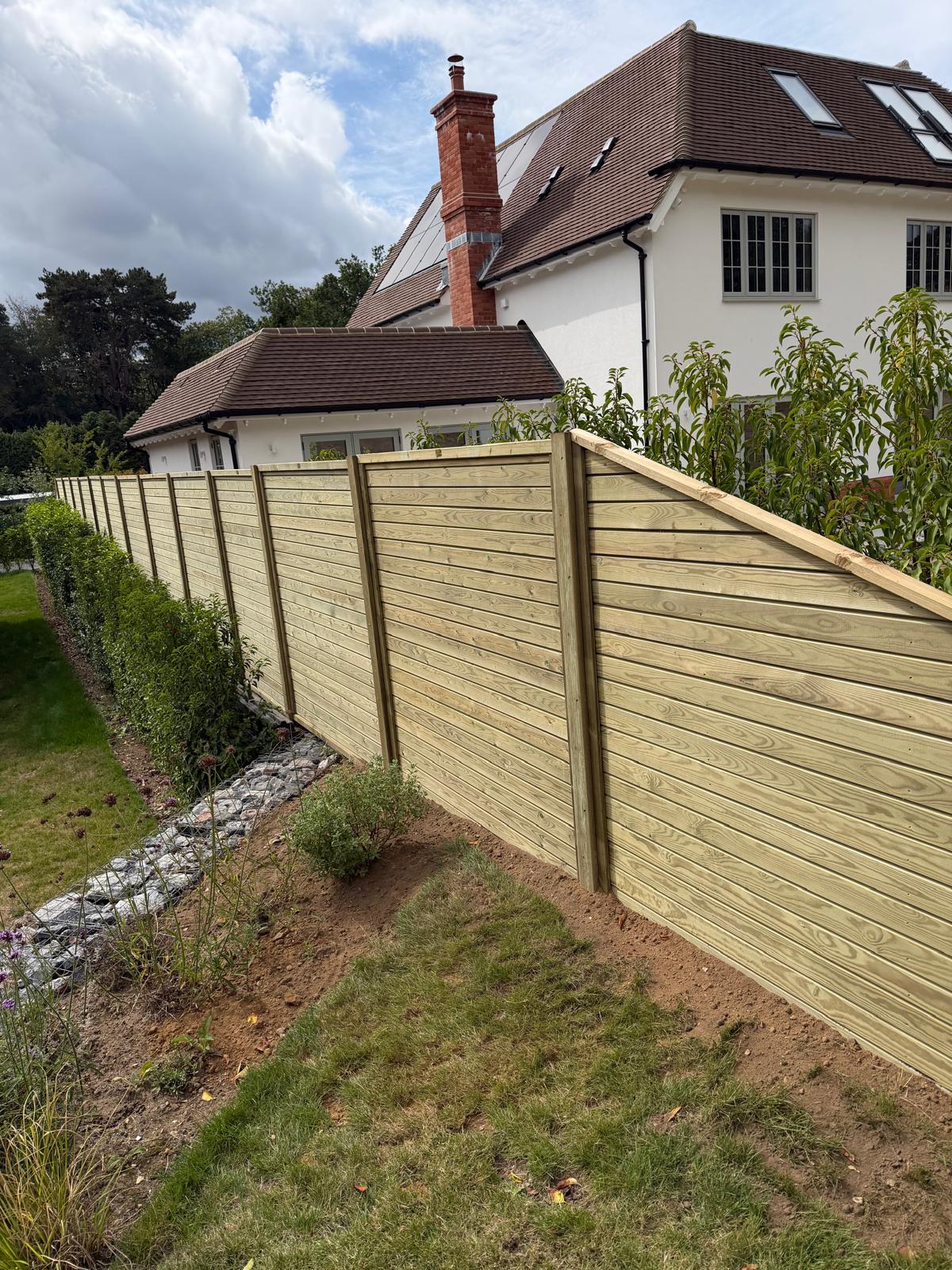 New tongue-and-groove timber fence panels along a residential garden boundary